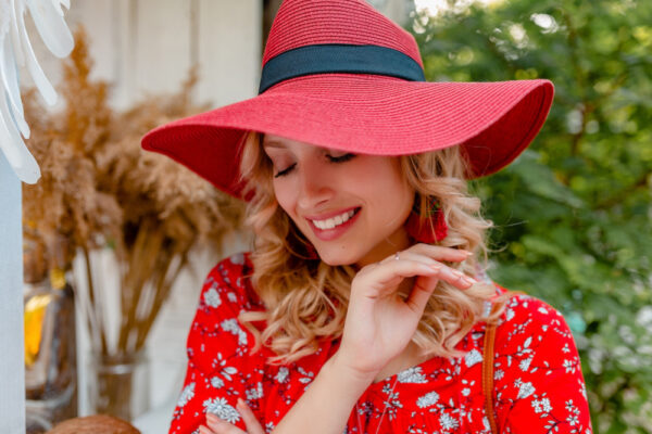 Femeie zâmbitoare cu pălărie roșie și rochie florală