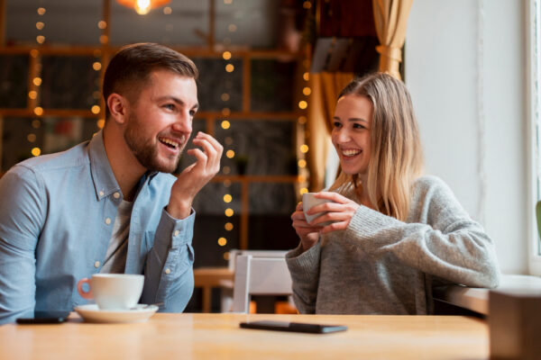 Cuplu zâmbitor discutând la cafea într-o cafenea