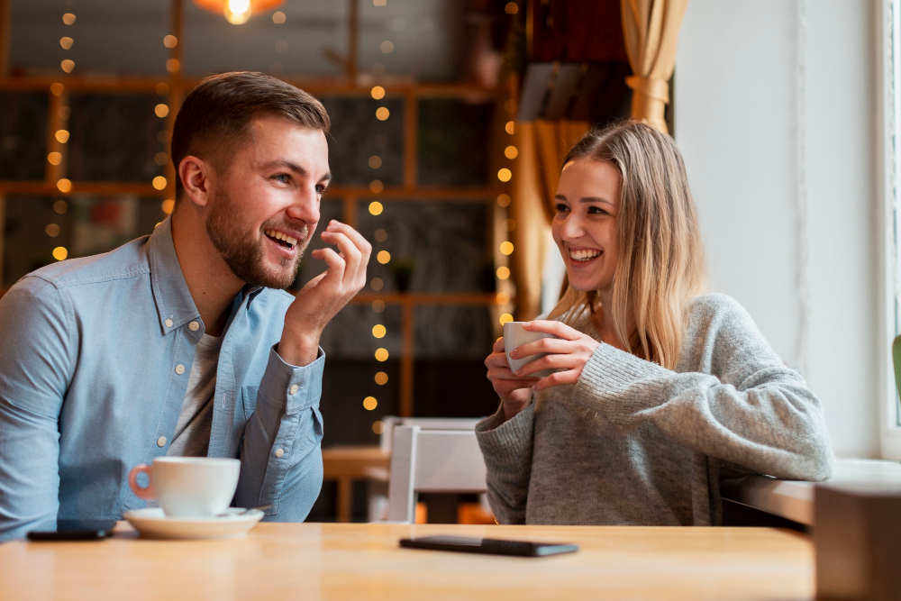 Cuplu zâmbitor discutând la cafea într-o cafenea